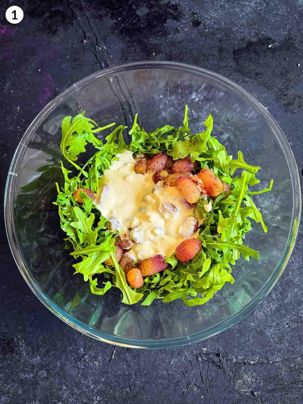 ingredients for Warm Arugula and Roasted Grape Salad with Blue Cheese in a clear bowl against a dark background