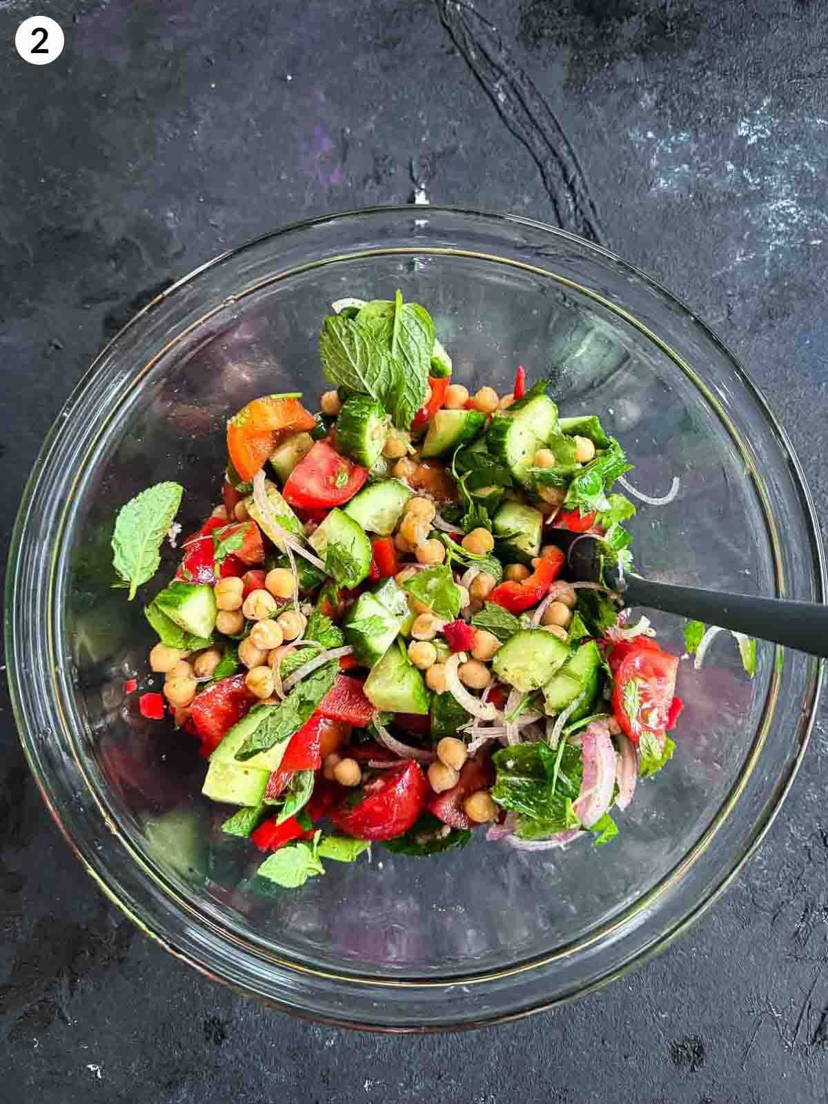 Balela Salad ingredients in a clear bowl with a spatula